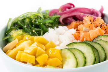Poke bowl with rice, salmon,cucumber,mango,onion,wakame salad, poppy seeds ands sunflowers seeds isolated on white background. Close up