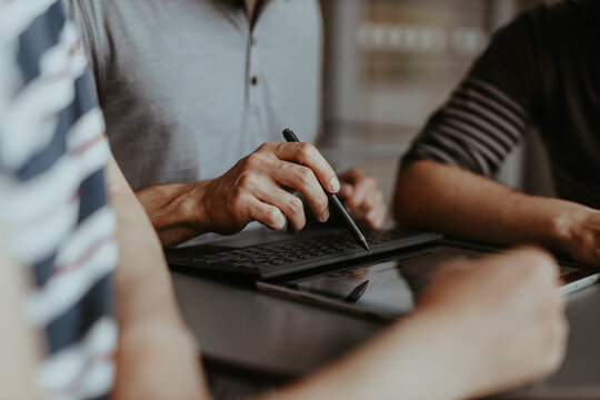 arbeitende H&auml;nde zeigen mit Stift auf ein Tablet 