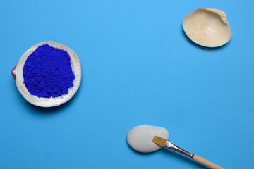 Distribución de dos conchas y una piedra sobre un fondo azul saturado, con pigmento azul cobalto y...