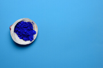 Interior de una concha llena de pigmento azul cobalto sobre fondo azul, el diseño distribuye el...