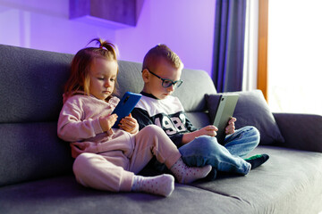 Danya and his sister Emilia play with mobile phones and tablets.