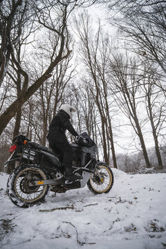 Motorcyclists enjoy extreme winter riding on a motorcycle, snowy forest, snowfall. The concept of transport and clothing for the cold season. Stupid ideas of grown men. Vertical photo.