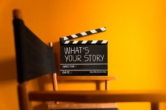 What's your story.text title on movie clapper board and director chair.Film clapper board or movie clapper cinema board , Slate film on black wooden with orange wall background .cinema concept