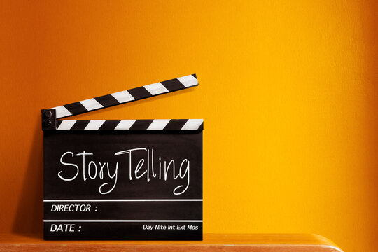 Story telling text title on film slate. Film clapper board or movie clapper cinema board , Slate film on black wooden with orange wall background .cinema concept	
