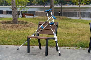 Medical crutches leaning on chair in empty city park. Concept of rehabilitation after injury.