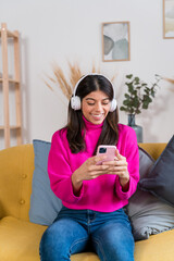Obraz premium Cheerful woman in headphones using smartphone