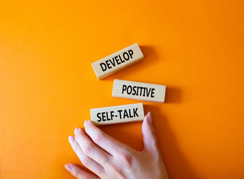Develop positive self-talk symbol. Concept words Develop positive self-talk on wooden blocks. Businessman hand. Beautiful orange background. Business and Develop positive self-talk concept. Copy space