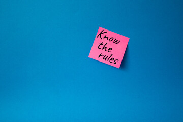 Know the rules symbol. Concept words Know the rules om pink steaky note. Beautiful blue background....