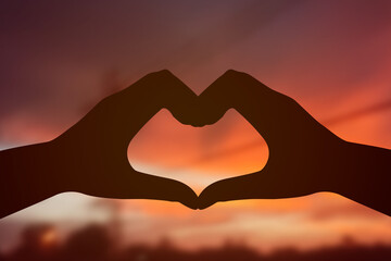 Silhouette. Hand made heart shape and beautiful evening sky.