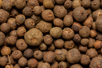 Close-up of brown allspice jamaica pepper grains. Texture of whole dried pimento berries. Concepts of organic spices, seasonings and condiments for cooking. Macro. Front view
