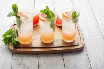 Summer refreshing fruit drinks with ice on a grey kitchen board