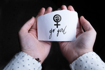 Point of view of a woman's hands holding a paper with the word Go Girl. Female empowerment concept