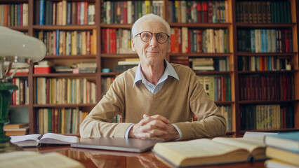 Inspired mature writer sitting in a library, completing last chapter of his new book