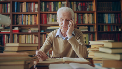 Senior researcher sharing information found in books with colleague on the phone