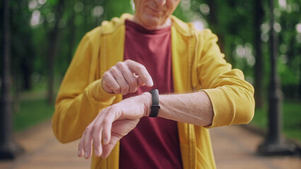 Smiling man in his 50s monitoring heart rate on fitness tracker, close-up