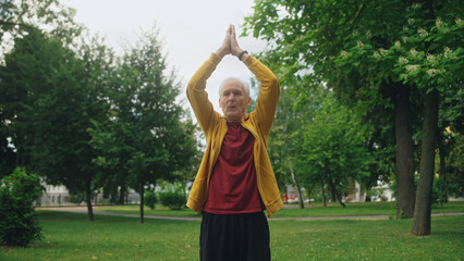 Senior man breathing deeply, practicing yoga in park, healthcare and vitality