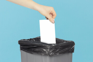 business card in an outstretched hand over a trash can, space for text. Throw away business card...