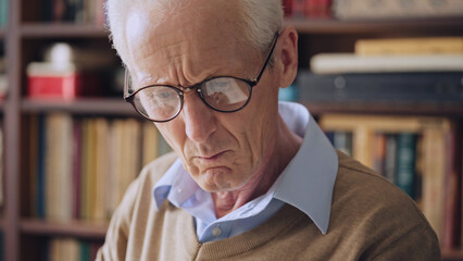 Mature male librarian reading a book with interest, literature and knowledge