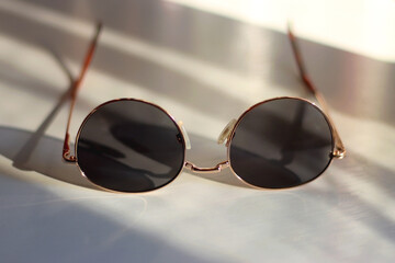 Retro round sunglasses on the table, illuminated by warm sunlight. Selective focus.