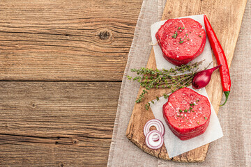 Raw Eye of round steak with spices and herbs on wooden background. Fresh meat for cooking food