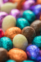 Fototapeta na wymiar Big pile of colorful wrapped chocolate easter eggs, shiny festive Easter concept, Happy easter close-up candy sweets concept macro