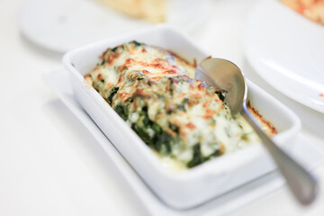 Baked spinach with cheese is easily made by smothering the spinach in cheese sauce and baking it until golden and bubbly