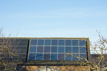 Brown roof with solar panels of a small shed with a clear blue sky