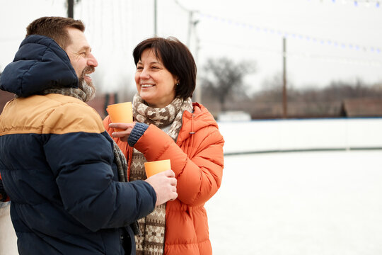 Middle-aged Couple, Man And Woman Visiting Open Air Ice Rink, Drinking Tea. Happy, Positive Day. Concept Of Leisure Activity, Winter Hobby And Sport, Vacation, Fun, Relationship, Emotions.