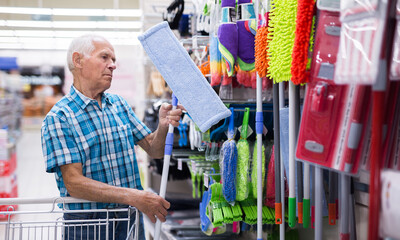 old age man examines mop in department of supermarket © caftor