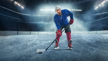 Obraz premium Hockey player on ice rink in sport arena field - stadium. Ready to shoot goal.