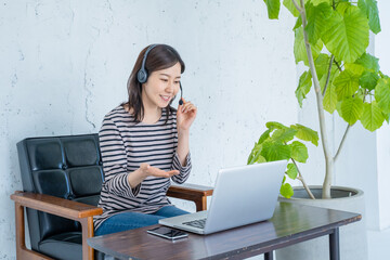 在宅ワークでヘッドセットをしてビデオチャットをする女性