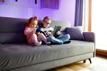 Danya and his sister Emilia play with mobile phones and tablets.