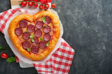 Valentines day heart shaped pizza with mozzarella, pepperoni and basil, wine bottle, two wineglass, gift box on black background. Idea for romantic dinner Valentines day. Top view. Mock up.