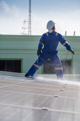 Obraz premium Technician using high pressure water to clean the solar panels that are dirty with dust and birds' droppings to improve the efficiency of solar energy storage.