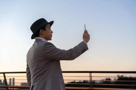 Asian businessman is using mobile phone to take pictures of the city view.
