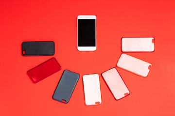 Choice of multicolored plastic back covers for mobile phones on red background with a smart phone on the side