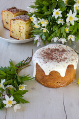 Easter Cake - Russian and Ukrainian Traditional Kulich or Brioche on a white wooden background. Easter cakes and spring flowers. Homemade cake with glaze.