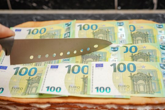 Festive cake with cream from euro banknotes. The cook cuts a piece of the money pie.