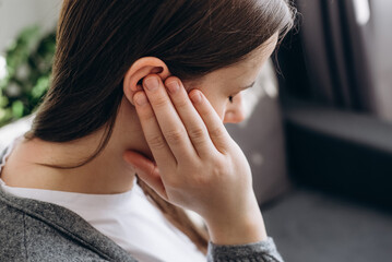 Close up of young brunette female holding painful ear, suddenly feeling strong ache. Unhealthy...