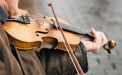 Old poor man playing the violin on the street, close up, street musician, copy space.