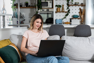 Young business woman home interior designer working on her laptop for new client who bought apartment and want improvement. Female Feng Shui expert looking on her computer design of furniture