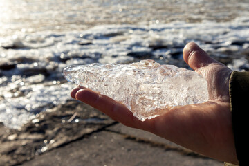 A frozen piece of ice on a person's palm on a sunny evening