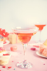 Romantic sweet dessert table with glass of pink wine, waffles, donut, ice cream, macaron, lollipop, candies. Valentine's day concept