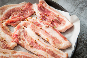 Whole pepper and raw pork belly in an oven pan