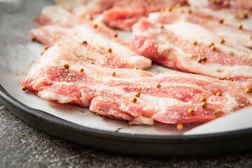 Whole pepper and raw pork belly in an oven pan