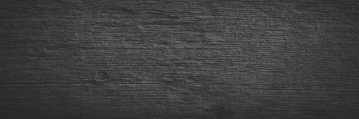Old wood texture. Weathered rough gray surface of a dry wooden beam. Faded dark wide panoramic background for design. Shaded vintage texture with vignette.