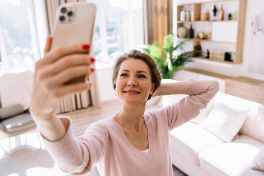 Smiling woman taking photo on smartphone