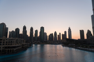 Obraz premium Dubai singing fountains at night lake view between skyscrapers. City skyline in dusk modern architecture in UAE capital downtown.