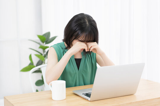 パソコンを使いながら泣いている若い女性