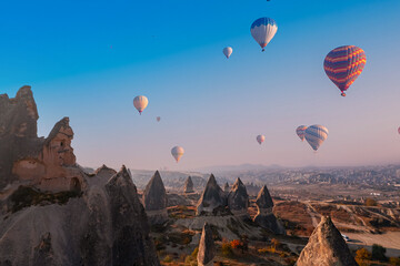 Fototapeta na wymiar Closeup ancient Goreme cave in big stone, hot air balloons fly over deep canyons, valleys Cappadocia National Park with sunlight, Turkey Travel